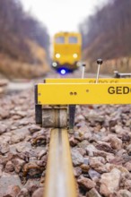 Close-up of a rail surveyor, a yellow vehicle in the background, tamping machine on the Hermann,