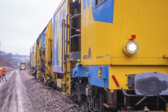 Several yellow work trains run along a rail route to maintenance, tamping machine on Hermann,
