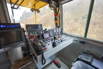 Interior view of a train driver's cab with numerous switch and control buttons, stuffing machine on