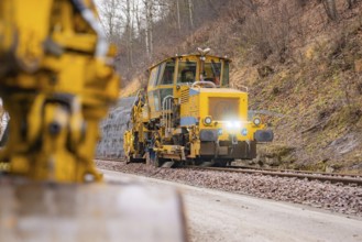 Rail construction machine in use on railroad tracks, indicated blur in the foreground, stuffing