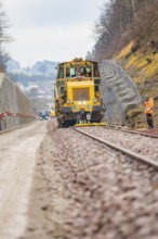 Machine and worker on rails during construction work in a rural area, tamping machine on Hermann,
