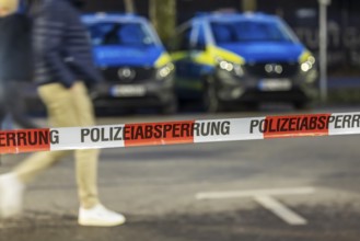 Flutter tape with the inscription police barrier. Behind them, police vehicles. Stuttgart,