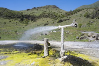Mineral water spring with vertical pipeline in hilly landscape under blue sky, Vardzia,