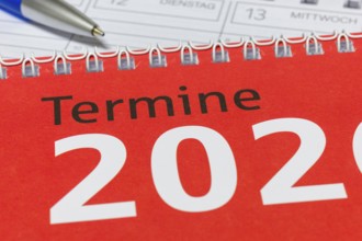 Close-up of a red calendar for 2026 with spiral binding and blue pen, diary