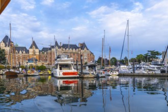 Luxury yachts and sailboats are moored in front of the fairmont empress hotel, reflecting in the