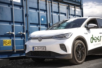 White car in an urban location next to a blue container, industrial atmosphere, VW ID4 electric