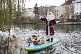 A water sports enthusiast dressed up as Santa Claus rides a SUP on the Spree in Berlin on 30.11