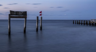Wooden sign in the sea with inscription Zingst and Buhnen, long exposure, evening light, Zingst,
