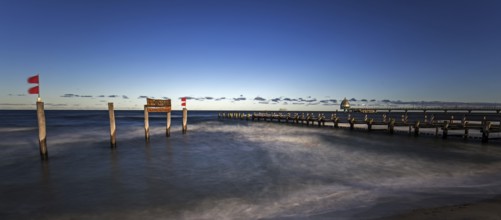 Wooden sign in the sea with inscription Zingst and Holzsteg, panorama, long exposure, evening