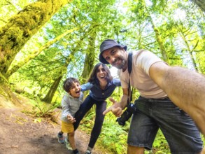 Happy family taking a selfie in the beautiful cathedral grove forest on vancouver island, british
