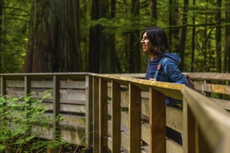 Woman enjoys a summer walk through the serene cathedral grove on vancouver island, canada. The lush
