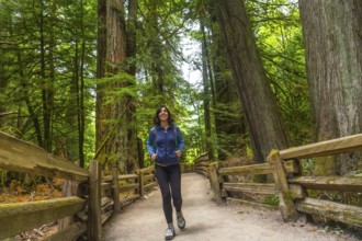 Female hiker enjoying a peaceful walk through the towering trees of cathedral grove on vancouver