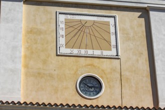 Sundial above and below masonry clock with hands, Italy