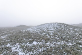 Mystical Celtic burial mounds in winter fog near Erkenbrechtsweiler. Snowy historic burial sites on