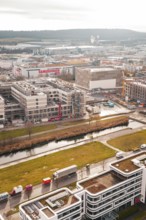 Urban construction site with buildings and river in the foreground under overcast sky, Böblingen,