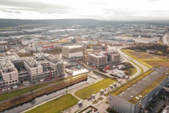 New hospital construction site with buildings and cranes near a river under cloudy sky, Böblingen,