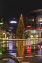 Illuminated Christmas tree and colorful lights in a rainy urban environment at night, Böblingen