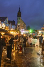 Lively Christmas market in rain with people and illuminated church in the background, Böblingen