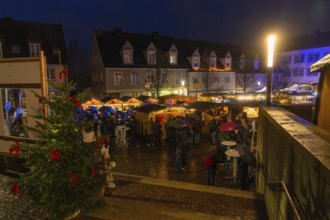 Christmas market at night, lots of visitors with umbrellas, Christmas tree and bright lights,