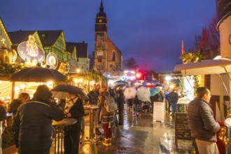 People with umbrellas and festive lighting at a Christmas market at night, Böblingen Christmas