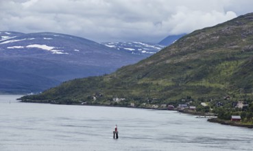 A quiet coastal strip with scattered villages in wooded hills and foggy skies, Norway