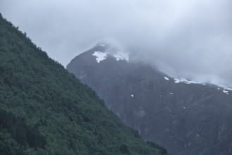 Mountain peak covered with snowspots and clouds, Norway