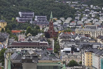A city view with a church in the center, surrounded by urban architecture and mountains Norway