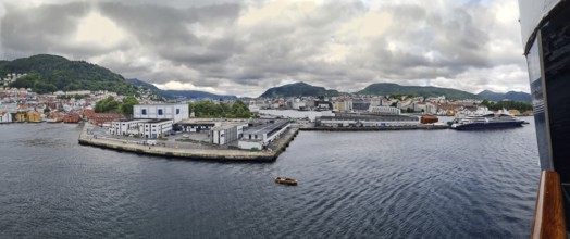 Extensive view of a harbor with ships and surrounding wooded mountains, mountains