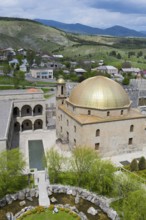 Mosque with golden dome and surrounding garden, nestled in a hilly landscape, Rabati Fortress,