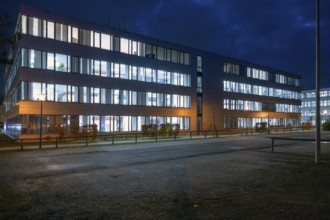 Siemens office buildings illuminated in the evening, empty parking spaces in front, Erlangen,