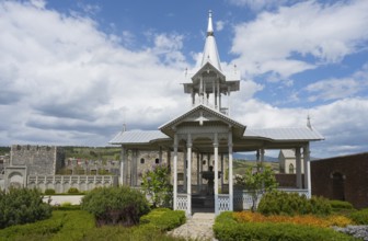 White wooden pavilion in a well-kept garden under a cloudy sky, Rabati Fortress, Akhaltsikhe,