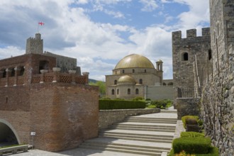 Historical building with golden dome and massive stone walls under cloudy sky, Rabati Fortress,