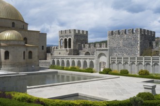 Stone building with golden dome, arcades and water basin in front of an imposing stone wall, Rabati