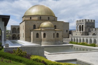 Buildings with golden dome and stone arcades next to water basins under blue sky, Rabati Fortress,