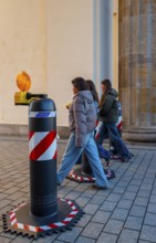 Passers-by at the security barrier made of massive bollards at the Brandenburg Gate passage,