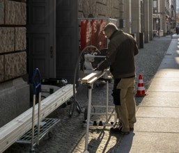 Craftsman with circular saw in the open air, Jägerstraße Berlin, Germany