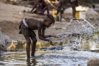 Himba child washing with water on a river, traditional Himba, Kaokoveld, Kunene, Namibia