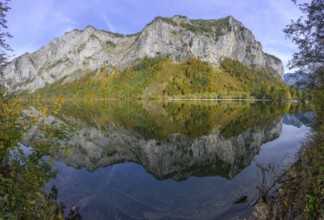 Rocks and autumn forest are reflected in the water of Lake Leopoldstein, Eisenerz, Styria, Austria