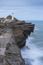 Castlepoint lighthouse on a rock, sea, long exposure. Castlepoint, Wairarapa Coast, Wellington
