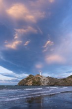 Castlepoint Beach, ocean and lighthouse on a rock, in the evening, dramatic sky. Castlepoint,
