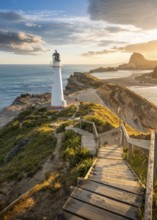 The Castlepoint lighthouse on a rock, ocean, Deliverance Cove and Castle Rock in the background.