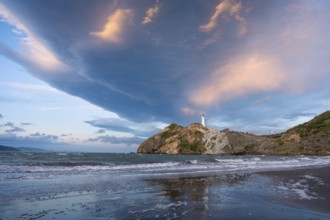 Castlepoint Beach, ocean and lighthouse on a rock, in the evening, dramatic sky. Castlepoint,