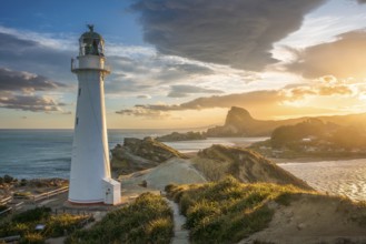 The Castlepoint lighthouse on a rock, ocean, Deliverance Cove and Castle Rock in the background.