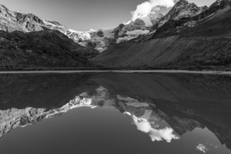 The Moiry glacier and mountain peaks are reflected in Lac de Chateaupre, black and white photo, Val