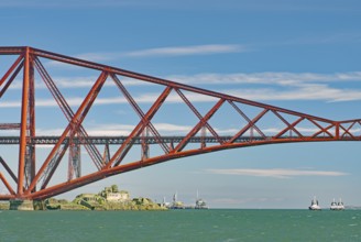 A section of a red bridge over a lake with passing boats, railway bridge, Firth of Forth,