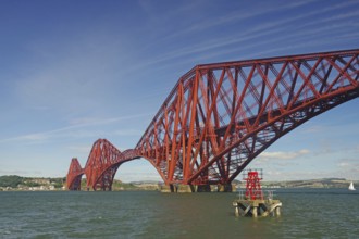 A distinctive red bridge spanning a wide river under clear skies, railway bridge, Firth of Forth,