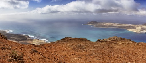 Wide coastline with blue ocean and sky, dotted with clouds overlooking La Graciosa, Haria