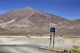 Lonely volcanic landscape with a sign to the beach under clear skies, Playa Blanca Lanzarote,