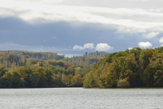 View over Lake Möhnesee, mixed autumn forest on the shore, rising rain clouds, Möhnetalsperre,