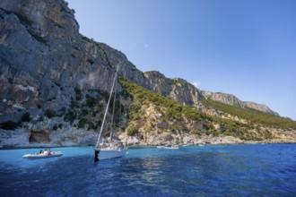 Picturesque rocky coast, sailboat off cliffs and blue sea at Piscine di Venere, Golfo di Orosei,